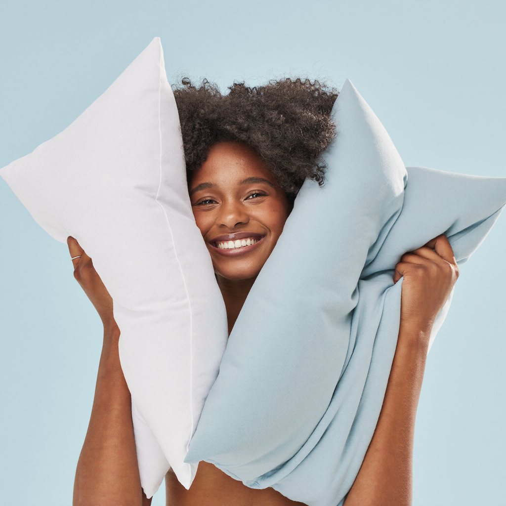 Joyful woman presenting white and icy-blue Frostmoor cooling pillowcases on a bright studio background