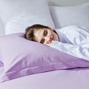 Woman sleeping peacefully on a plush lavender Frostmoor cooling pillow in a bright bed